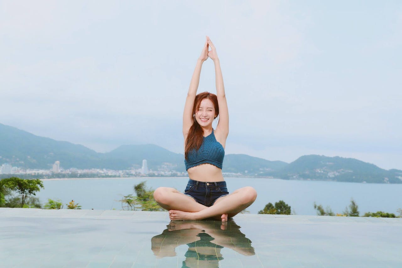 services-01 Young woman doing yoga by a scenic waterfront, enjoying a serene landscape.
